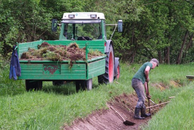 Der Landwirt reinigt den Graben von altem Bewuchs
